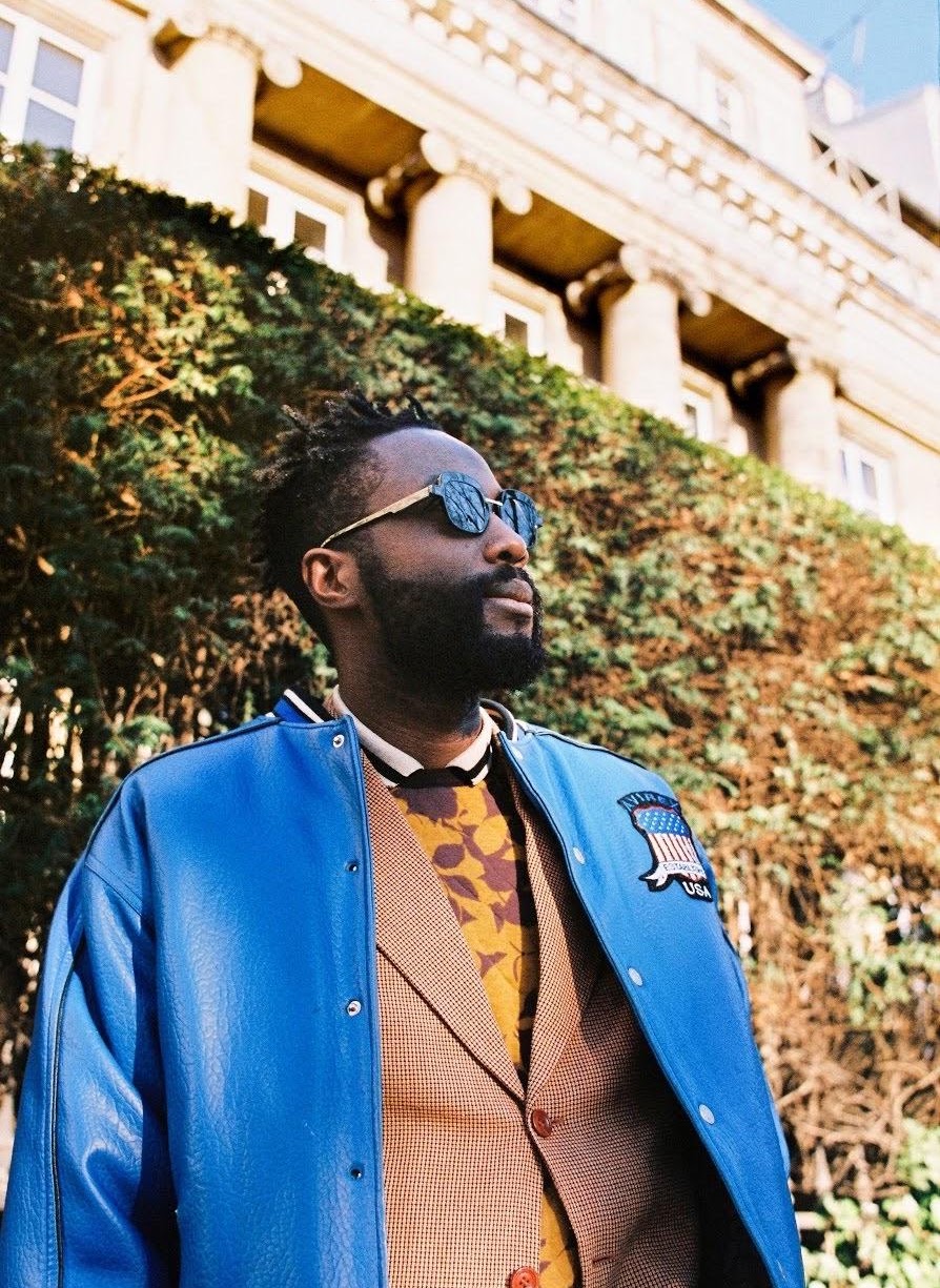 André On’okoko en veste bleue et lunettes de soleil